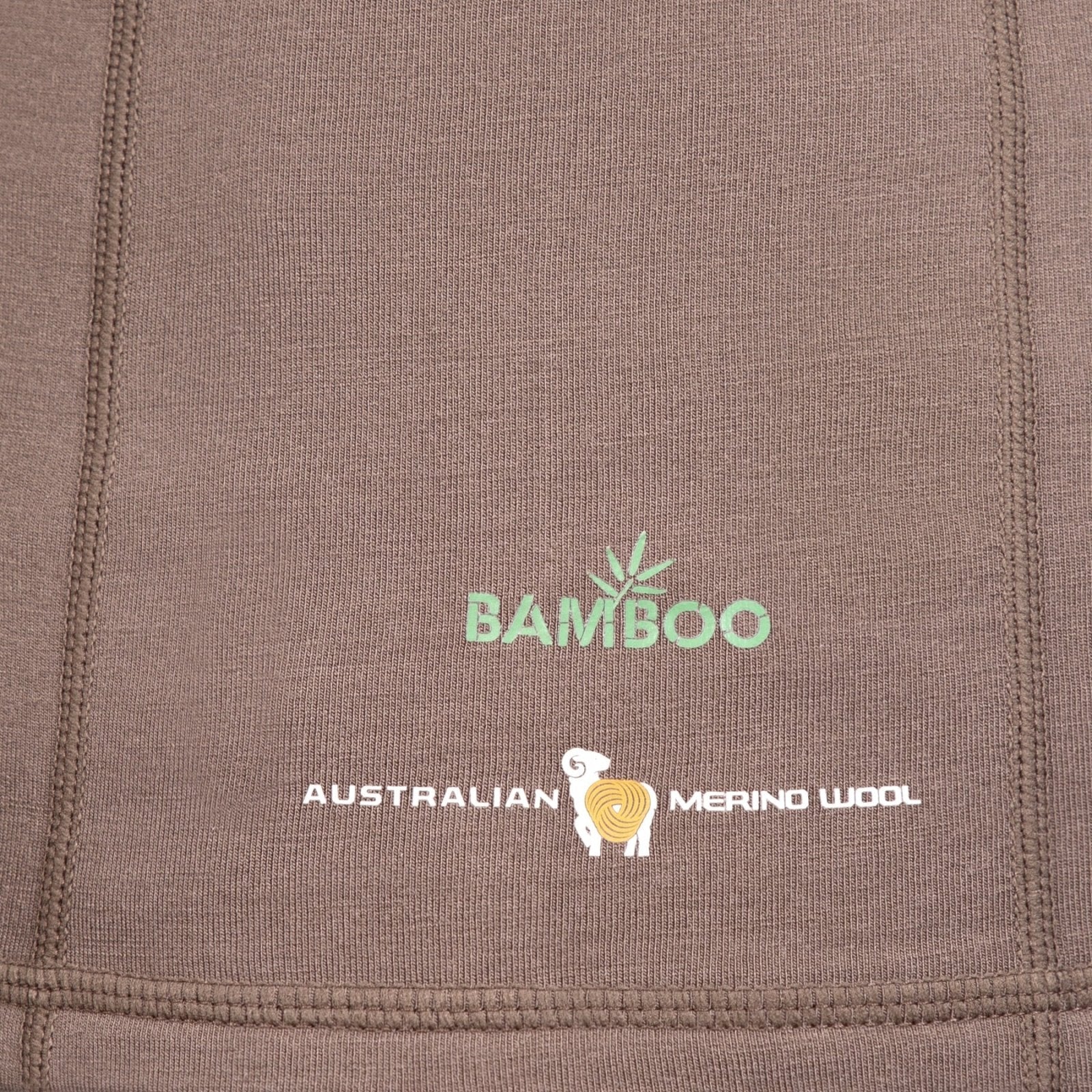 Близък план на кафяв плат от Hillman 3ML Ловен суитчър, със зелен текст "Bamboo" и листо. Отдолу бял текст "Australian Merino Wool (мерингосова вълна)" с жълто-бяло лого на овца. На шевовете е показана терморегулацията Synertech™.